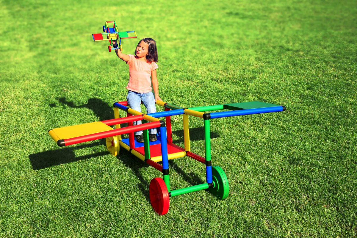 Child playing with a toy plane on a colourful QUADRO wheeled frame outdoors