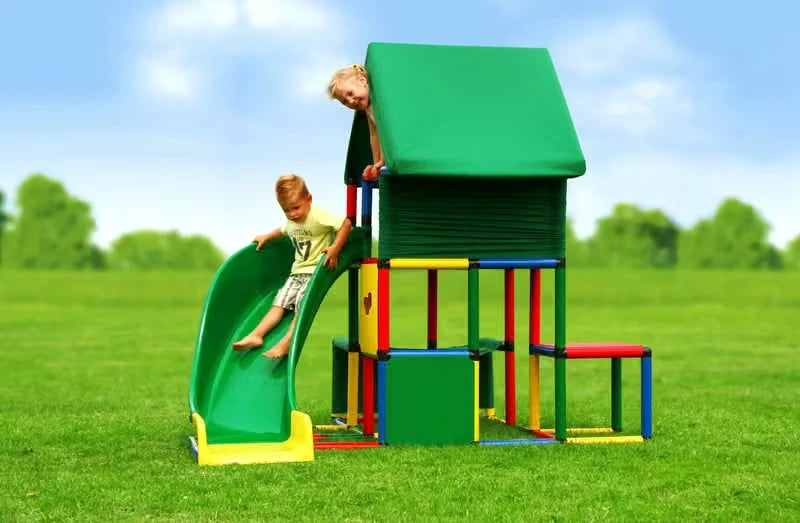 Two children using a green curved slide on a covered QUADRO play tower