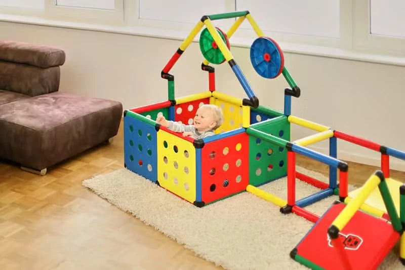 Baby seated in a QUADRO playpen with coloured perforated panels