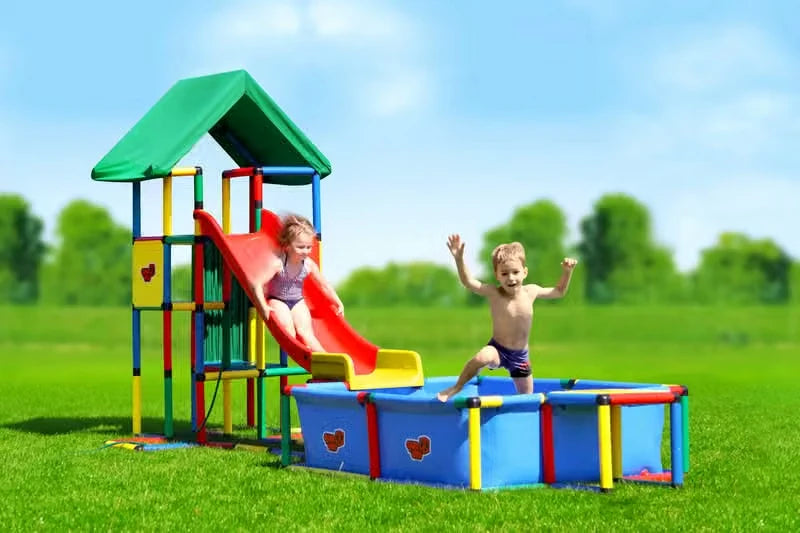 Two children using a modular red slide that ends beside a QUADRO pool