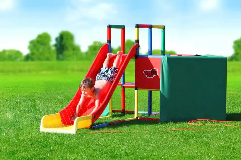 Two children sliding together on a modular red QUADRO slide beside a play cube