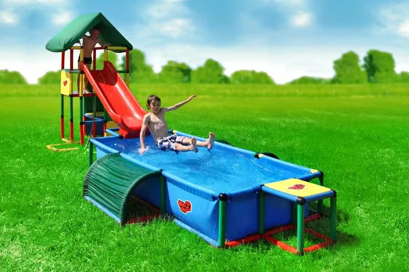 Child splashing in an XXL QUADRO pool beside a modular red slide